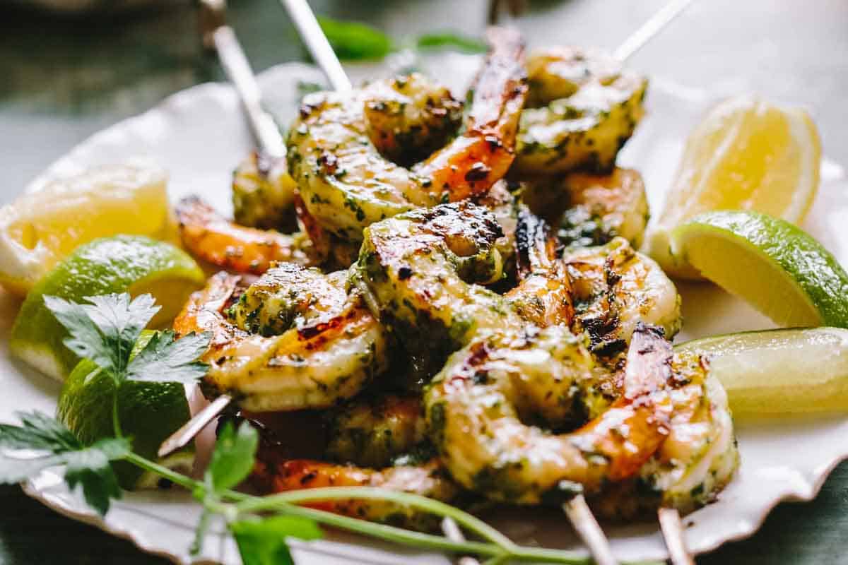Citrus marinated grilled shrimp on skewers with herbs and limes.