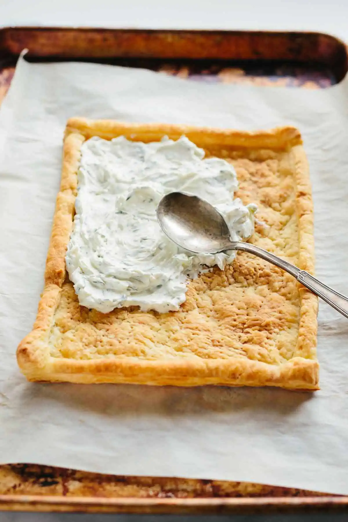 Spreading cream cheese on baked puff pastry.