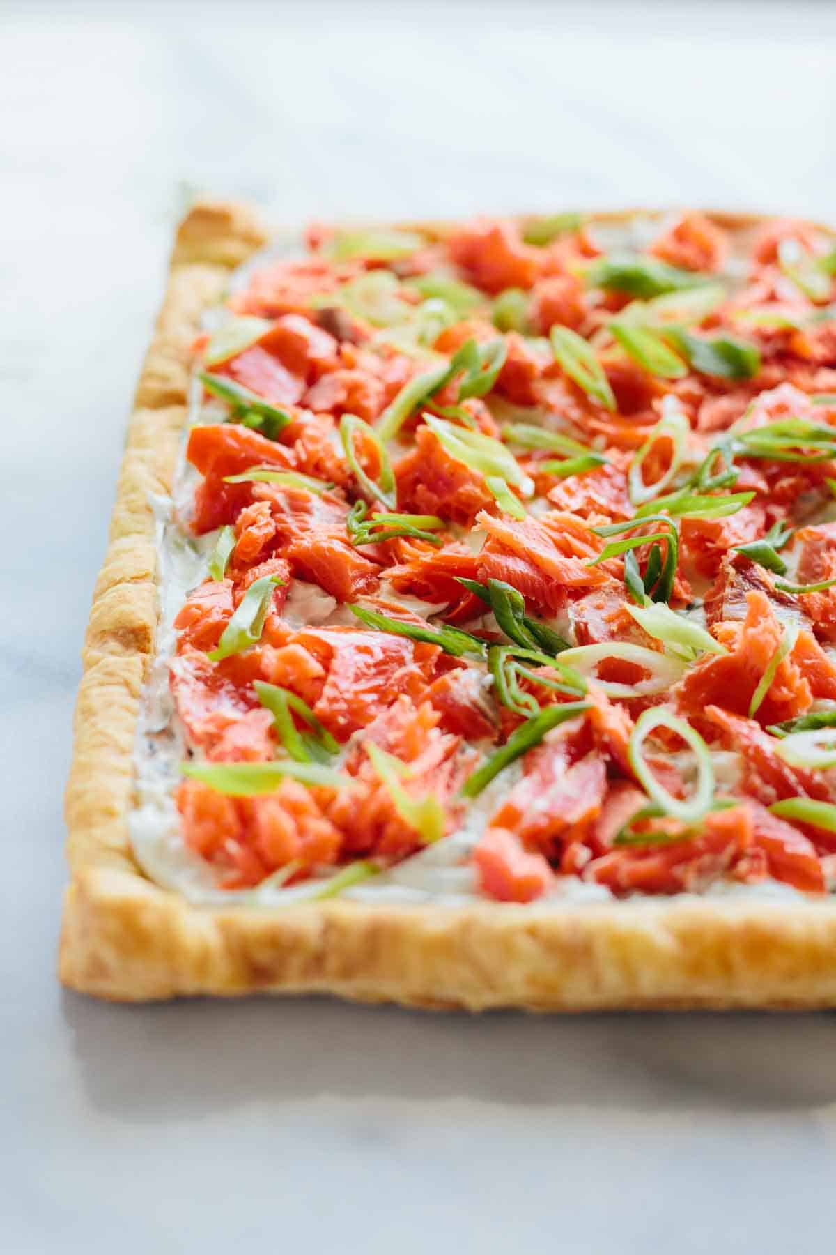 A whole smoked salmon tart with scallions on top.