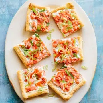 A platter with smoked salmon tart cut into squares.