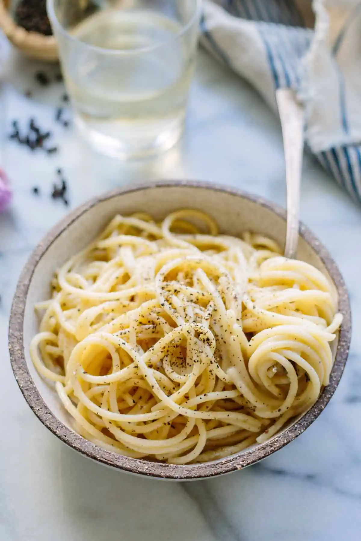 A bowl of spaghetti cacio e pepe with a fork twirling pasta.