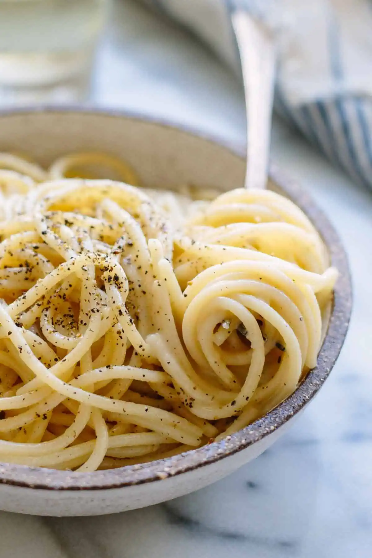 Close up of a fork that has twirled up some spaghetti cacio e pepe.