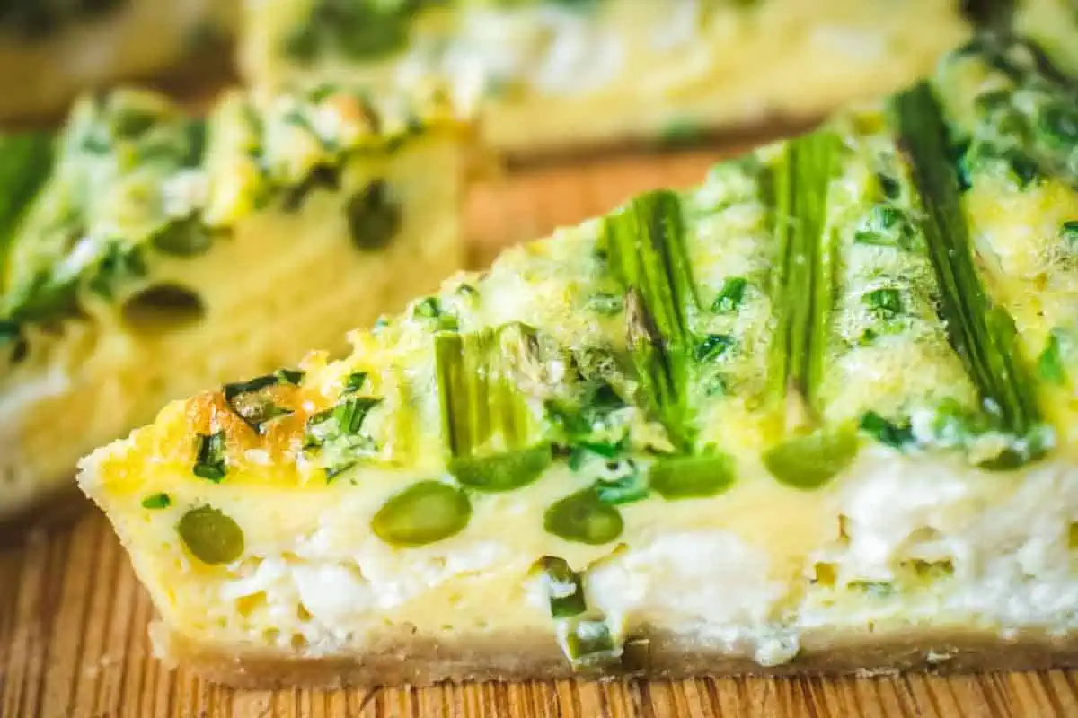 Pieces of asparagus and goat cheese inside a slice of quiche.