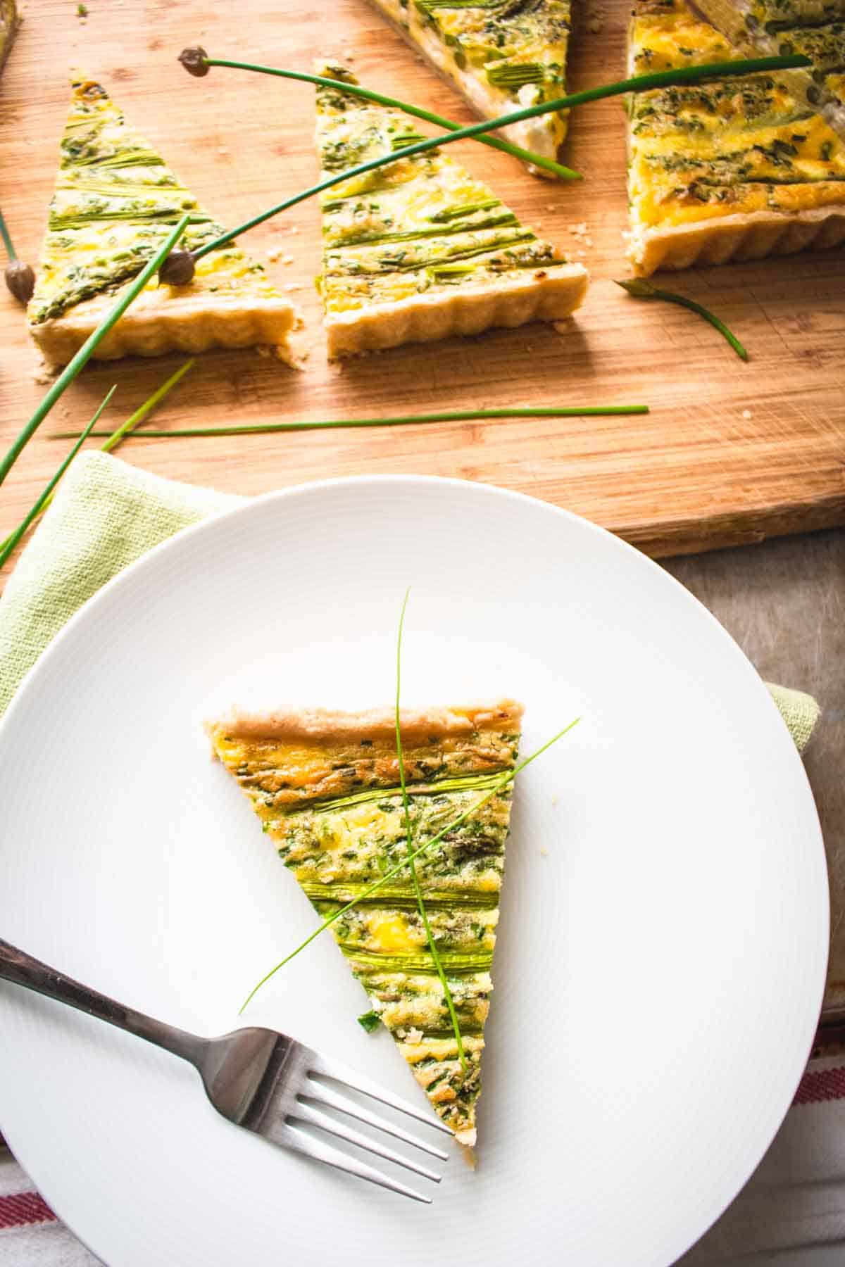 A slice of asparagus quiche on a white plate.