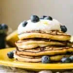 A stack of fluffy pancakes with a dollop of ricotta and fresh blueberries.