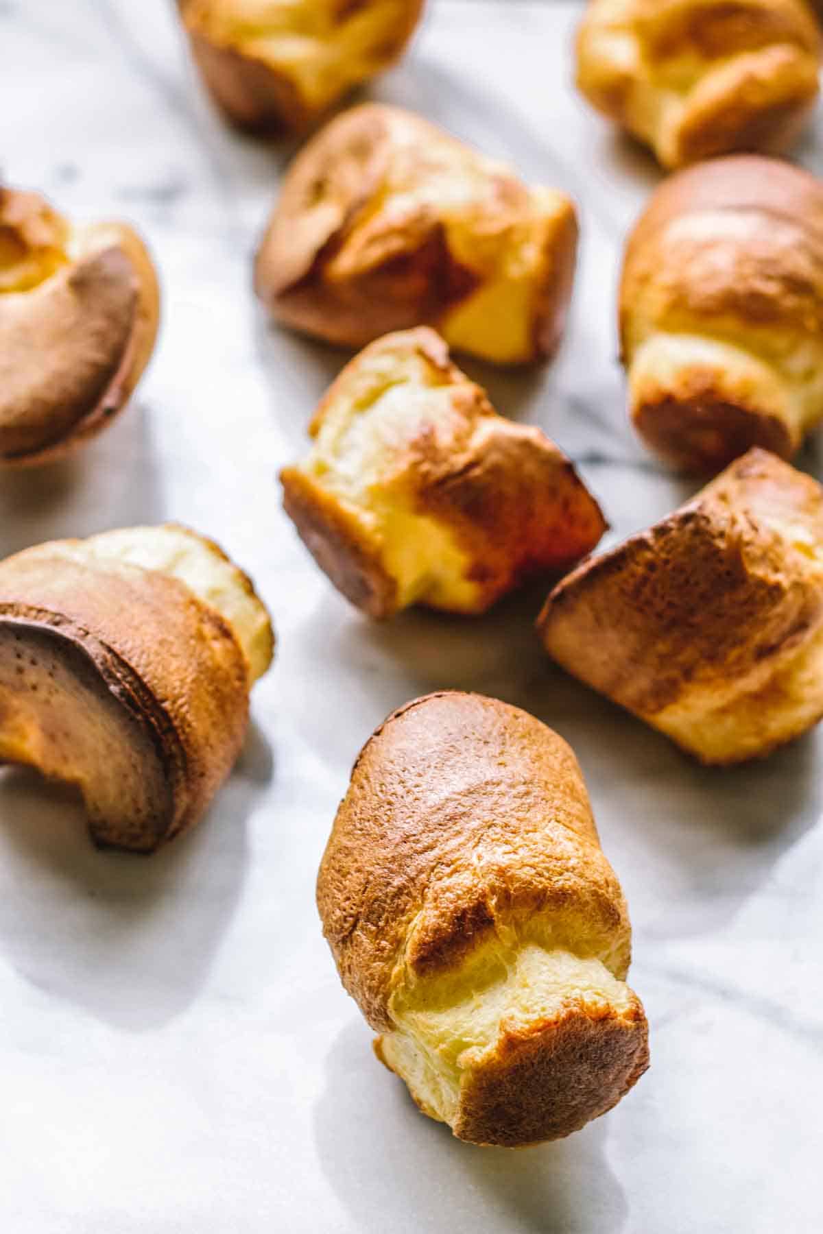 Freshly baked popovers splayed out on a marble board.