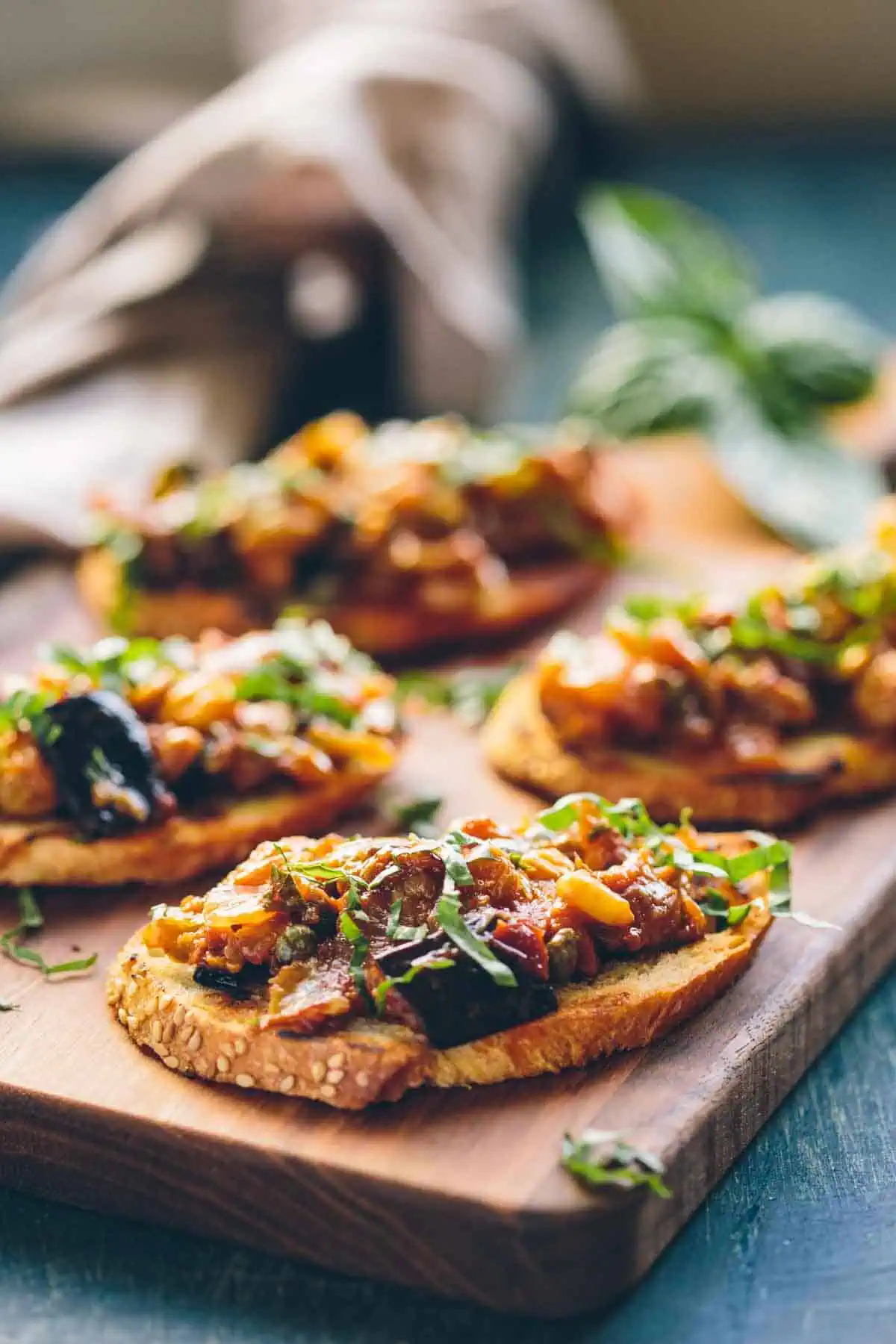 A serving tray of crostini topped with caponata with pine nuts and raisins.