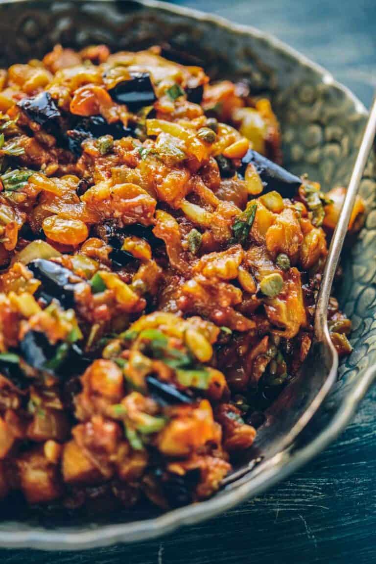 Eggplant caponata in a gray serving bowl with a spoon.