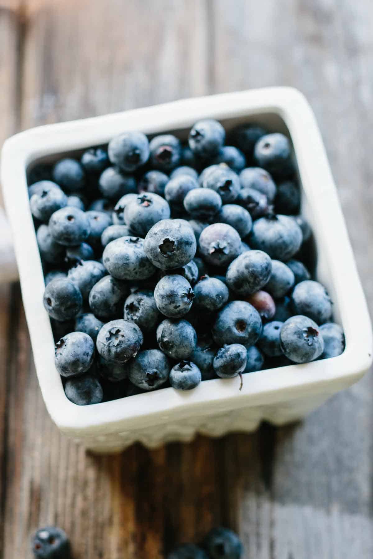 A ceramic pint container filled with fresh blueberries.