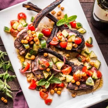 Grilled marinated Lamb Chops with vegetables and chick peas on a platter.