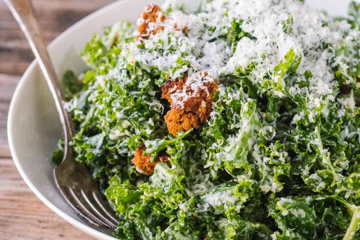 Leafy green kale Caesar salad with cheese sprinkled on top.