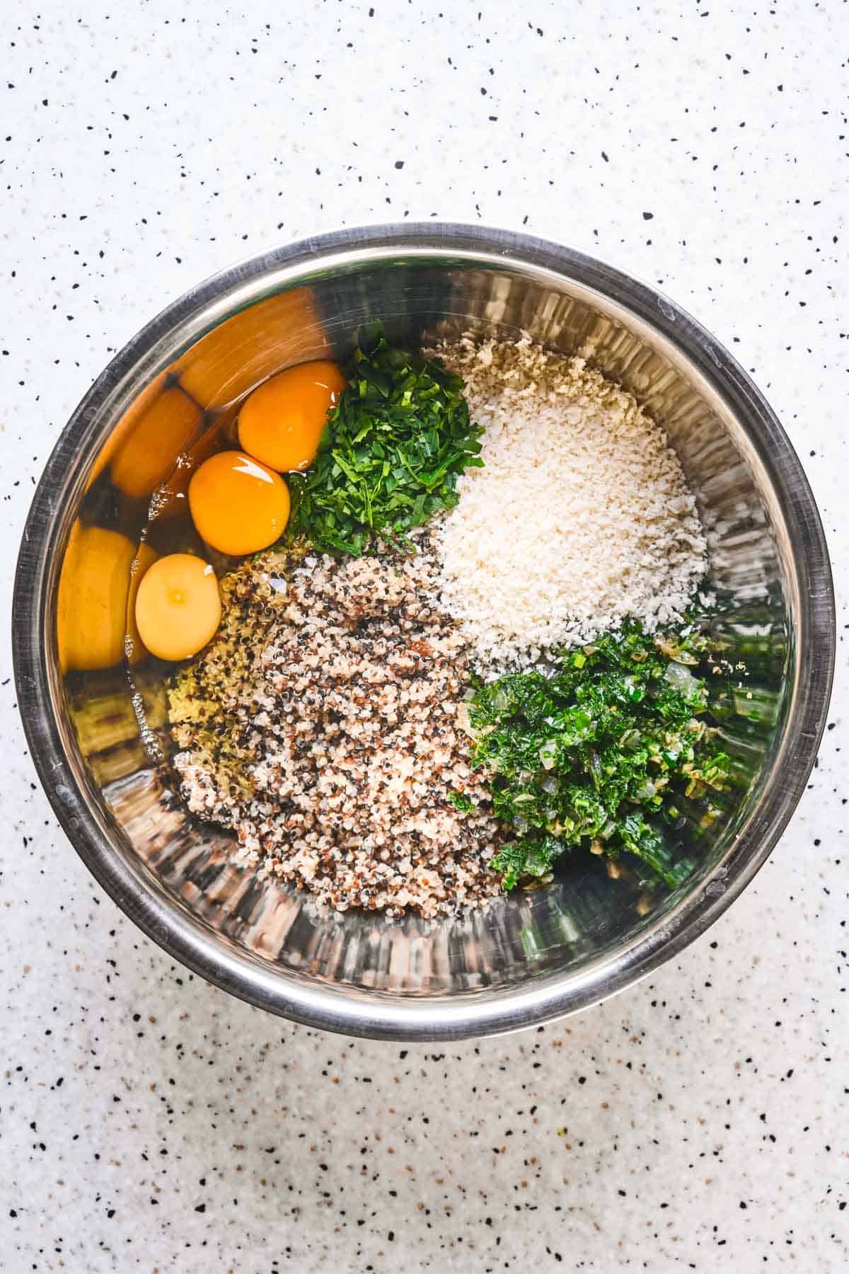 Eggs, kale and seasonings being added to a bowl of quinoa.