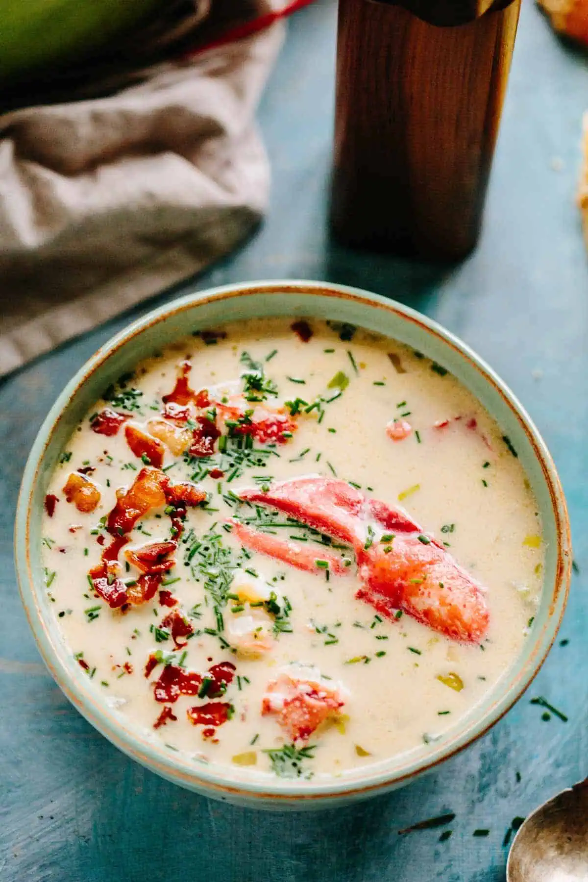 A bowl of New England lobster chowder with bacon and chives on top.