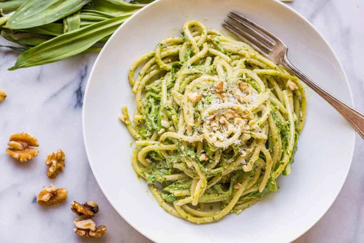 A shallow white bowl filled with ramp pesto pasta and shaved asparagus.