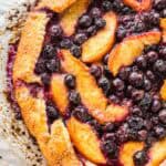 Sliced peaches and blueberries inside of a rustic pie crust,
