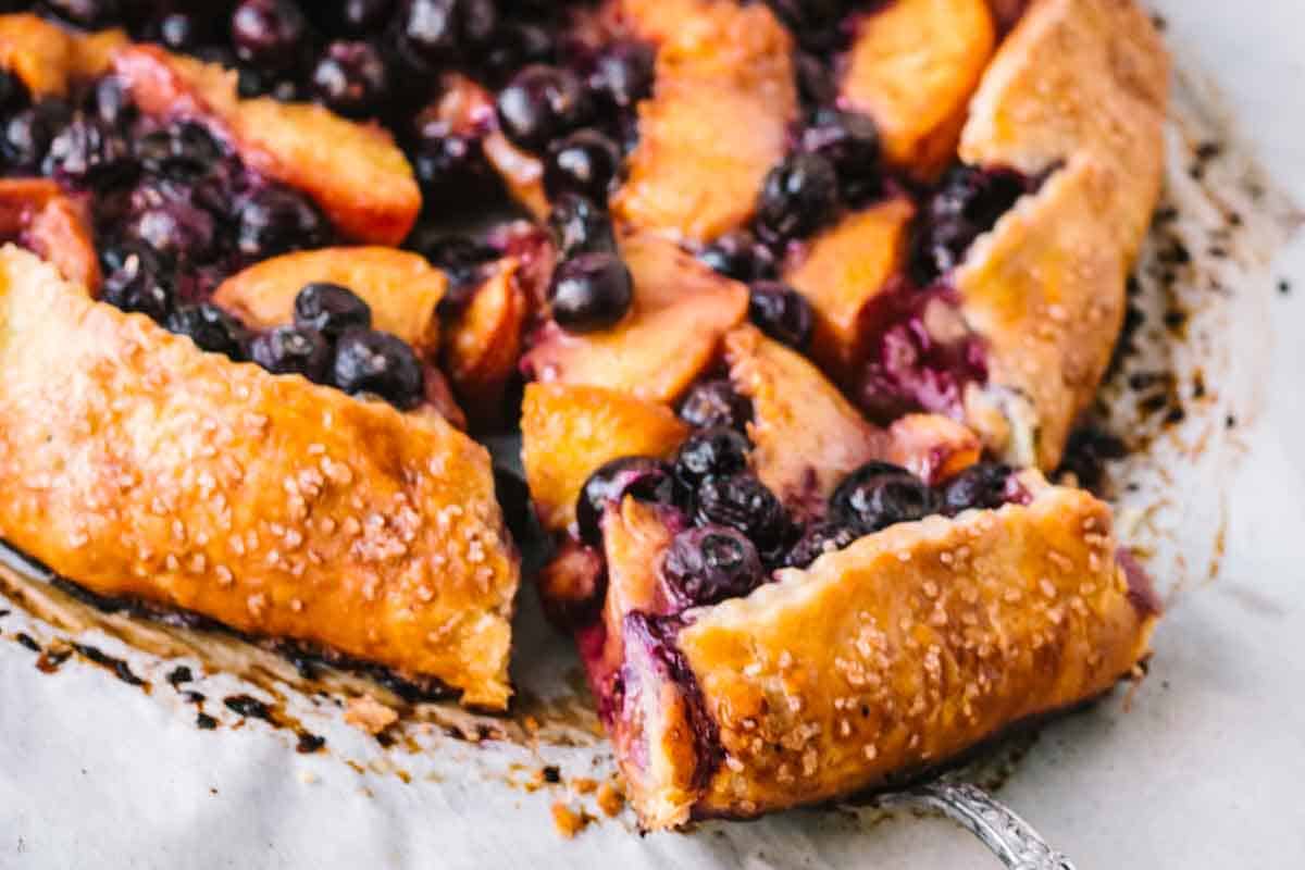 A blueberry peach galette with a slice pulled out.