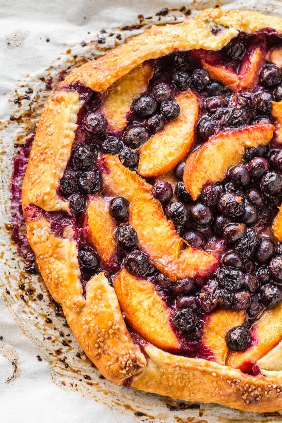 Sliced peaches and blueberries inside of a rustic pie crust,