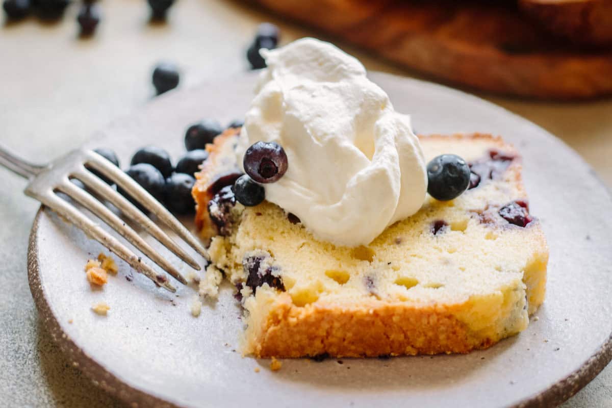 A slice of partially eaten lemon blueberry pound cake with a fork.