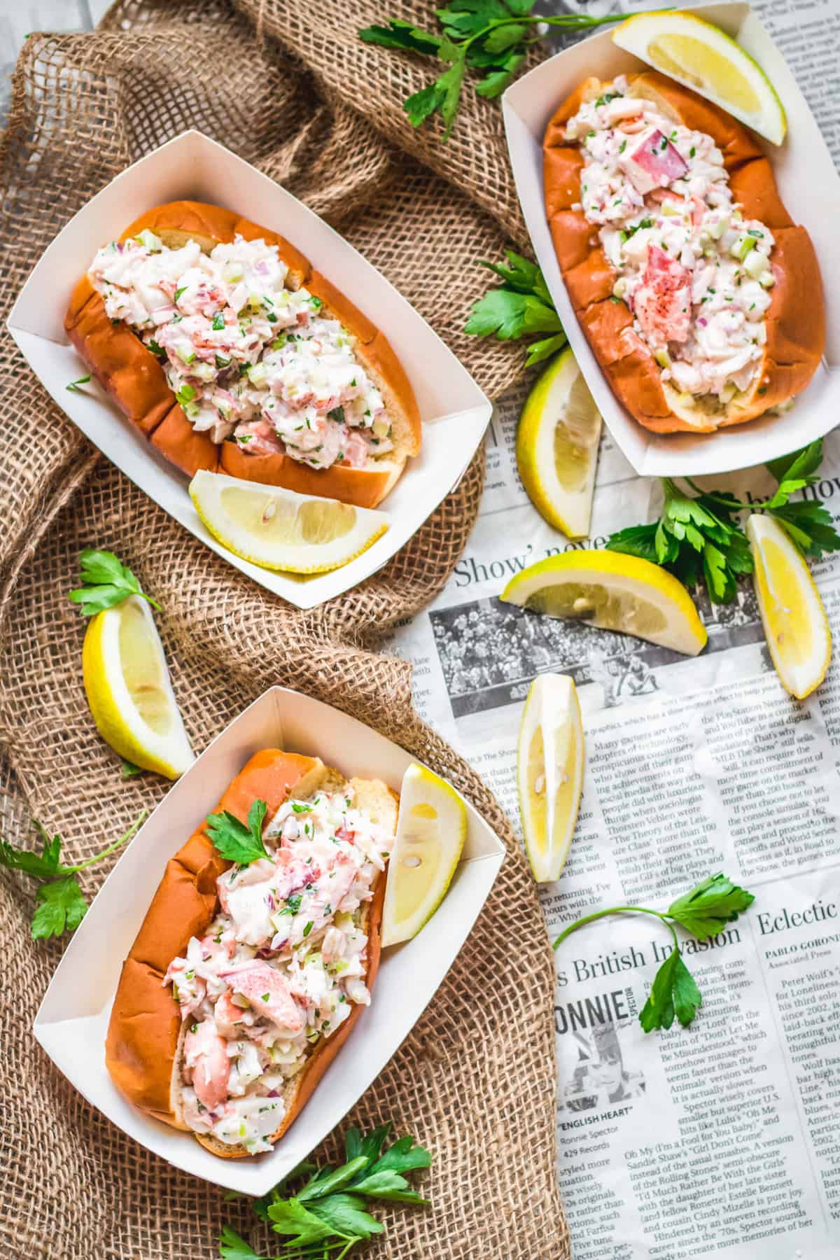 Three classic Maine lobster rolls in paper food boats.