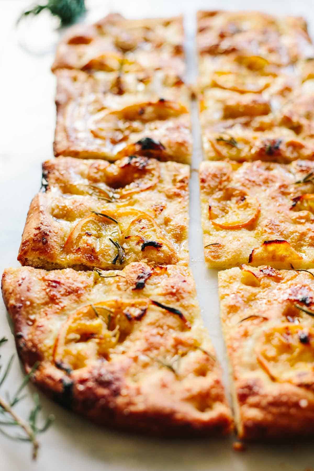 Slices of focaccia with lemon, herbs and sea salt on top.