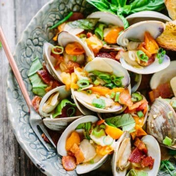 A bowl of steamed clams with bacon and tomatoes.