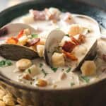 A close up of opened clams in a bowl of clam chowder.