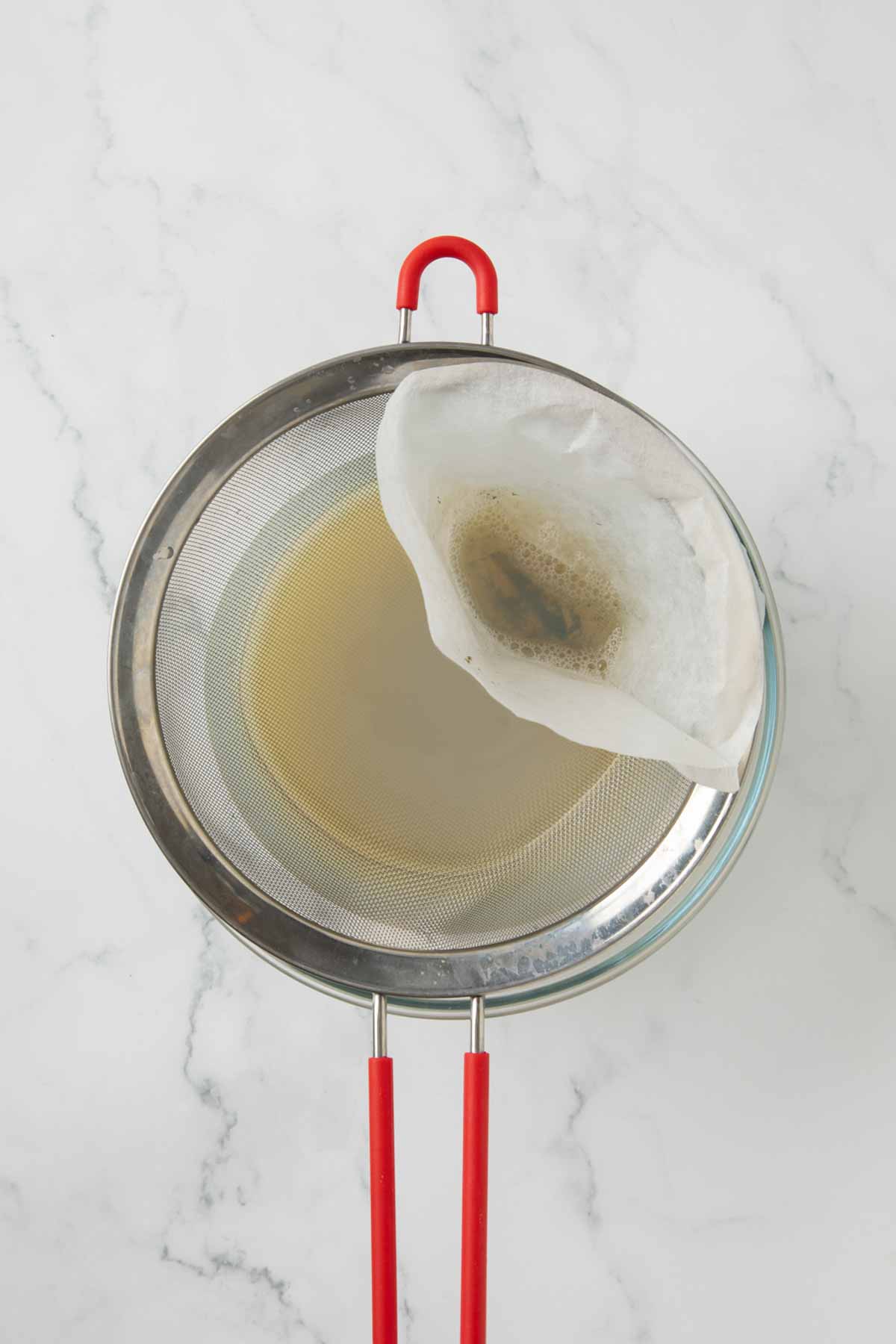 Strained clam juice with grit and sand in the strainer.