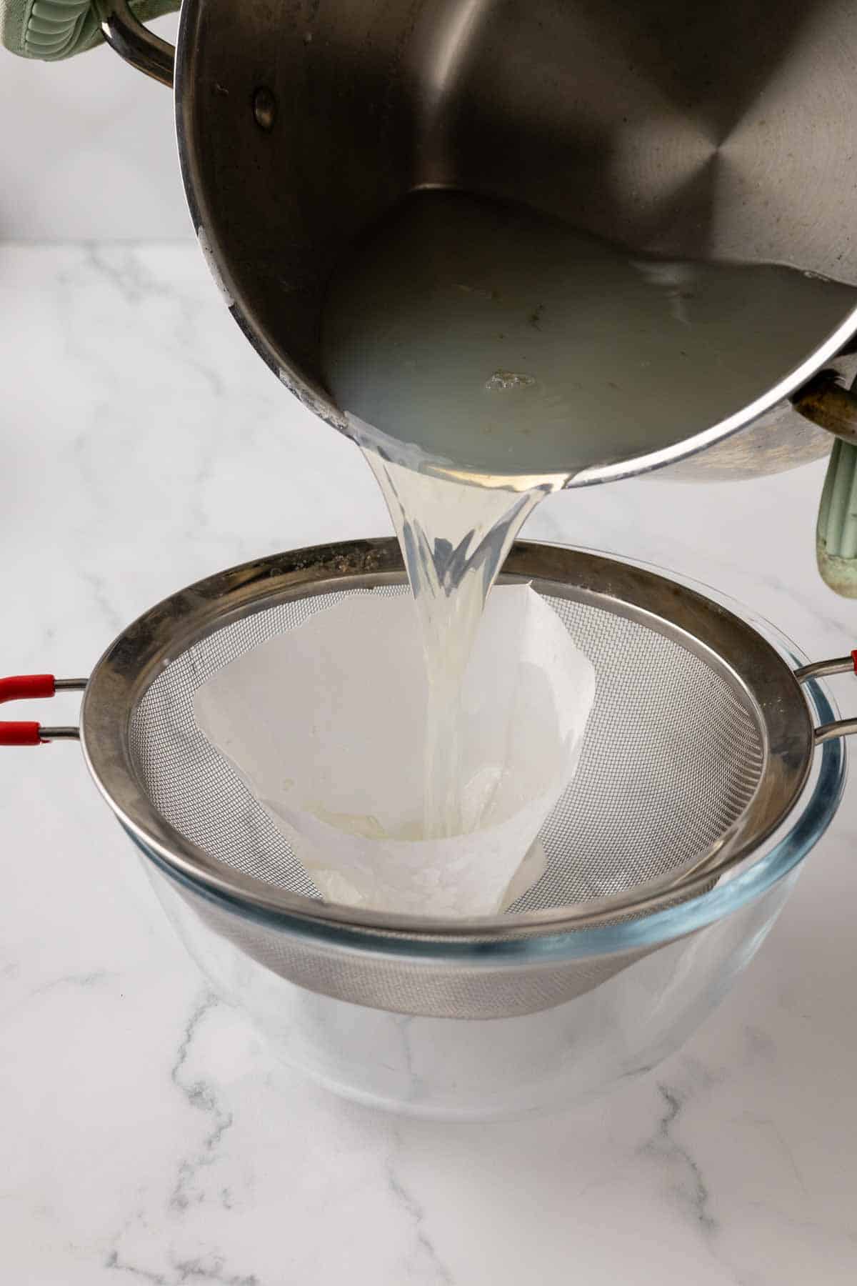 Pouring fresh clam juice through a strainer.
