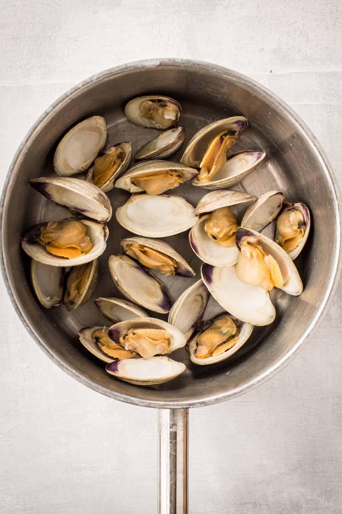 Fresh clams cooking in a stainless steel pot.