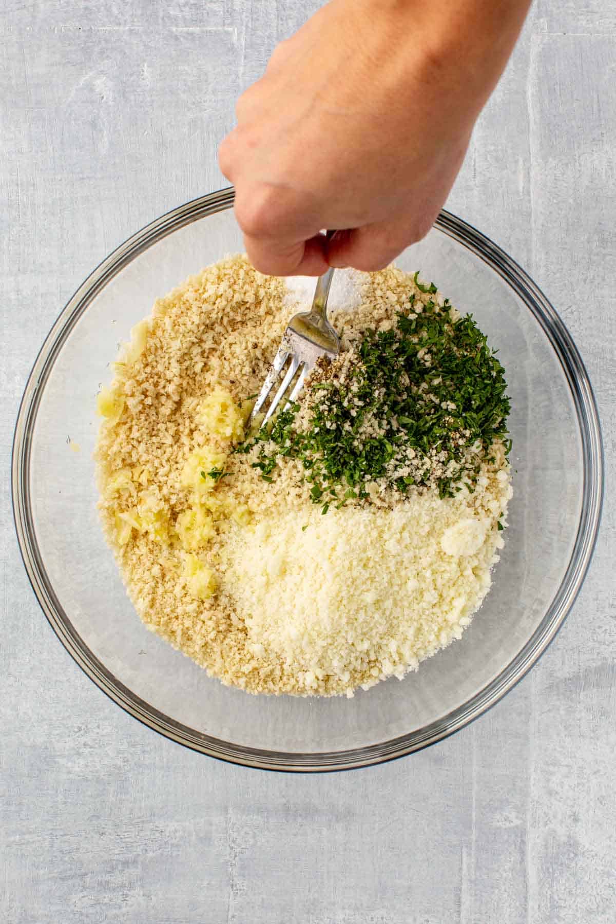 Mixing breadcrumbs together with a fork.