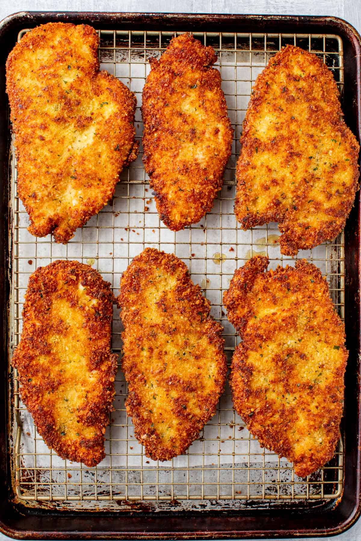 Crispy chicken cutlets cooling on a wire rack.