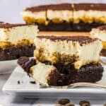 A few slices of tiramisu brownies on plates, one has a bite taken out with a fork.