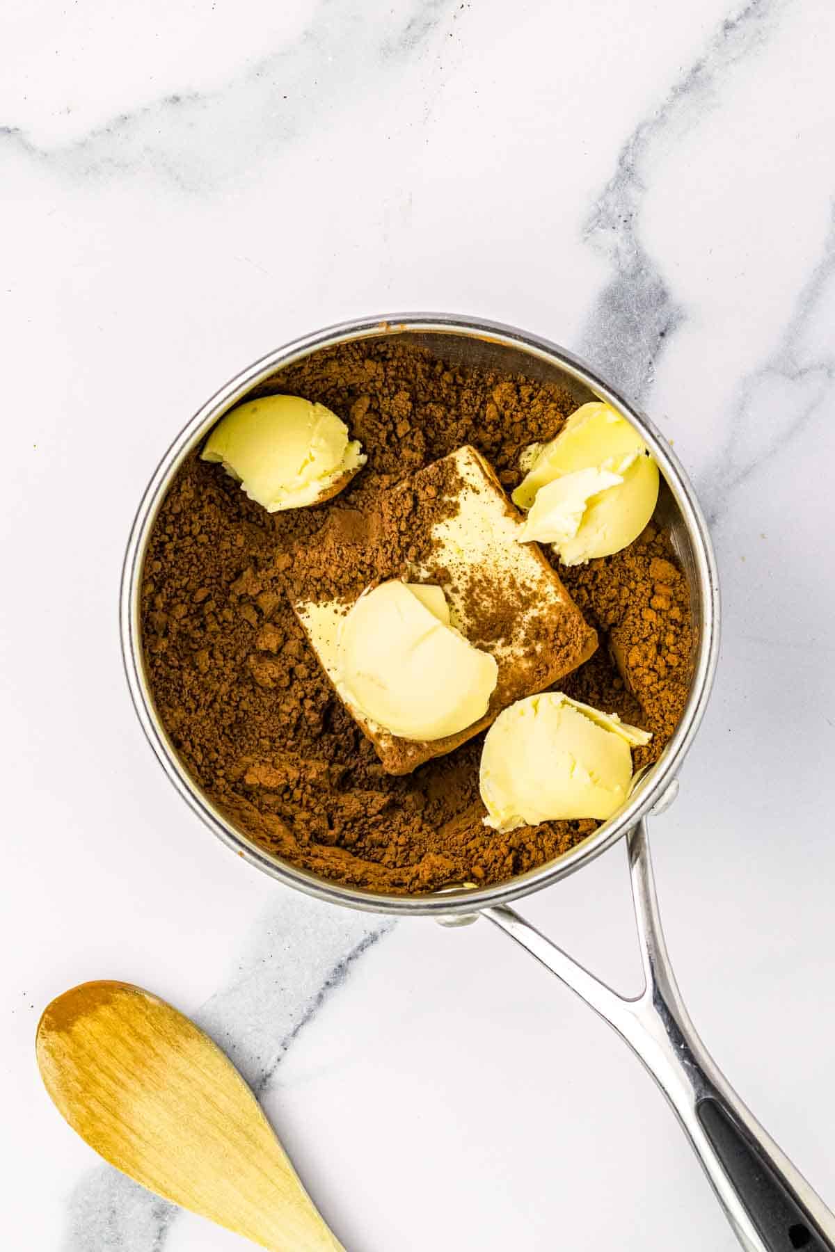 A small saucepan with butter and cocoa powder.