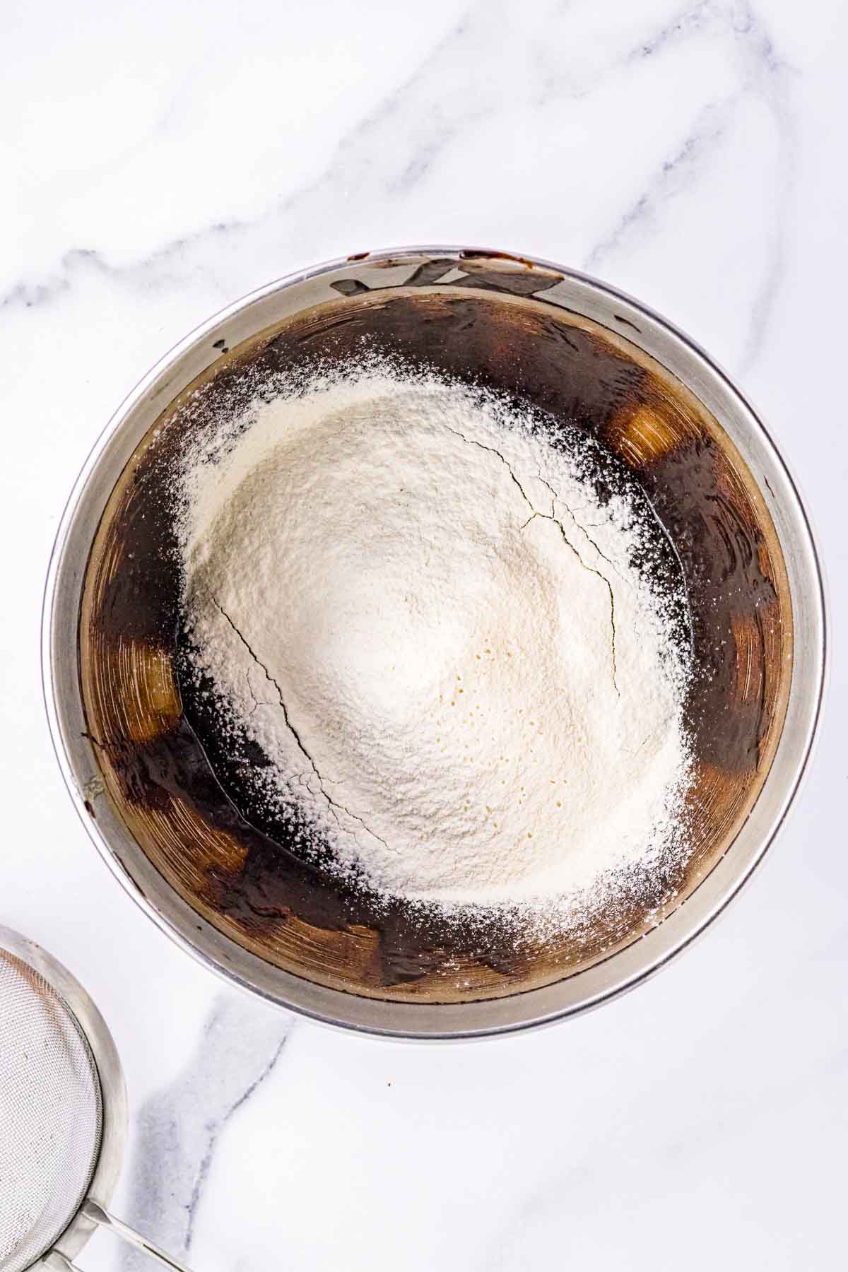 A bowl with flour being mixed into a chocolate mixture.