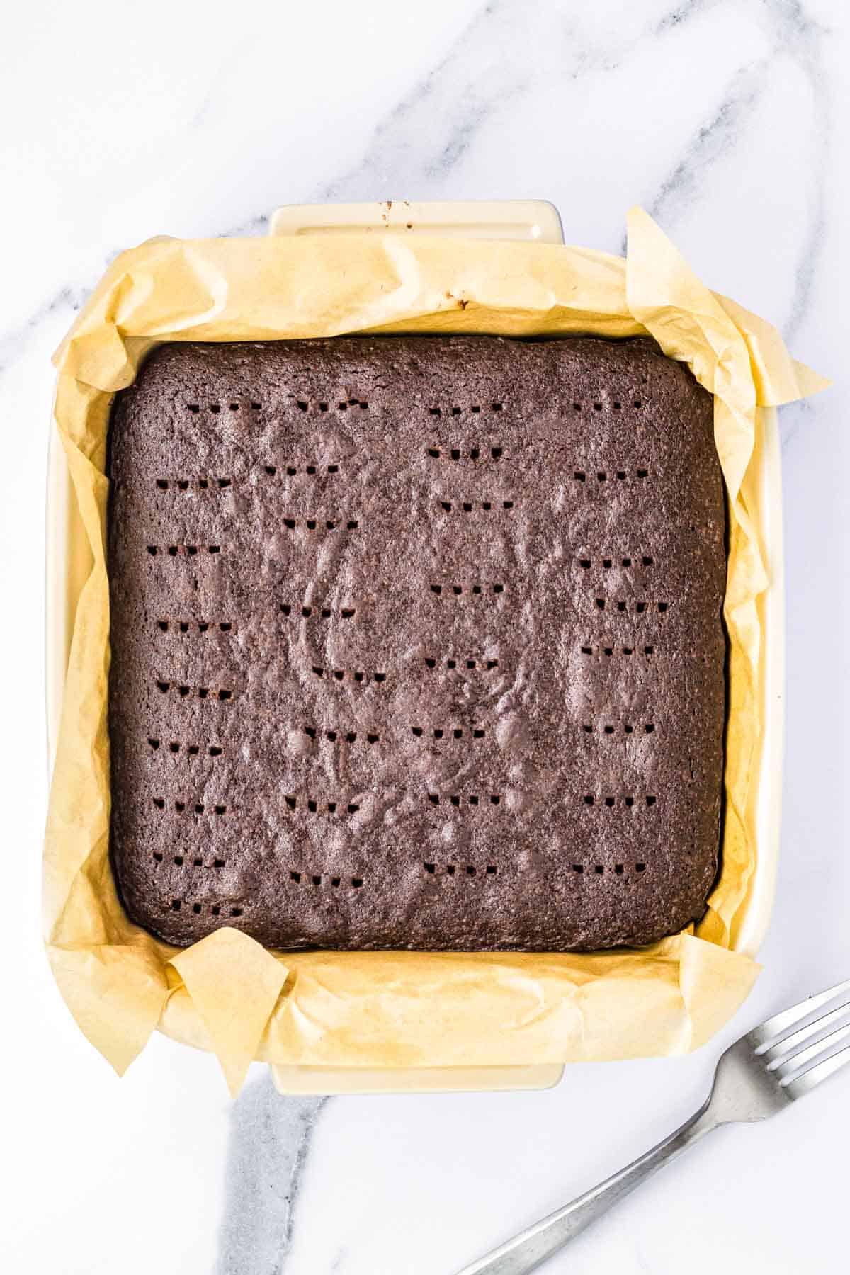 A pan of brownies with holes poked in the top.