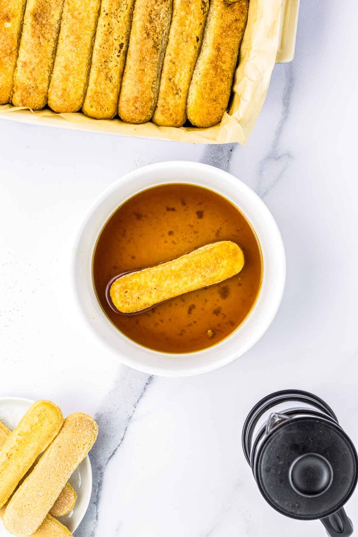 A lady finger cookie soaking in sweetened espresso.