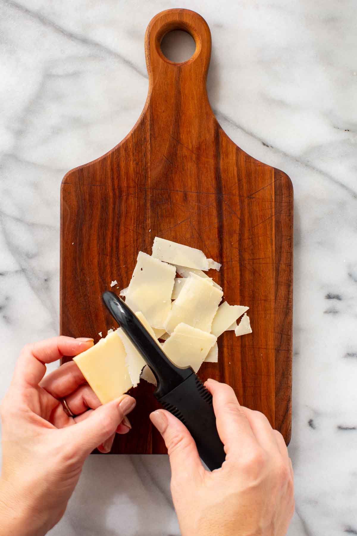 Shaving parmesan cheese with a vegetable peeler.