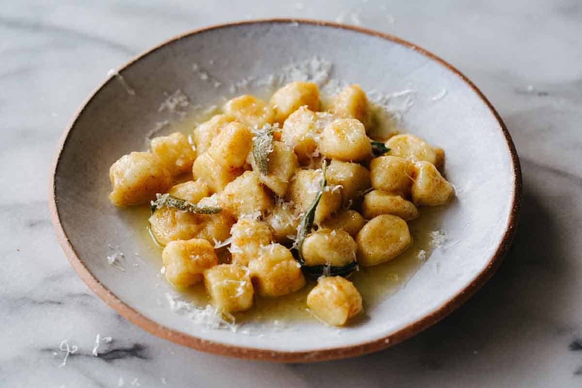 A plate of gnocchi in brown butter sauce.