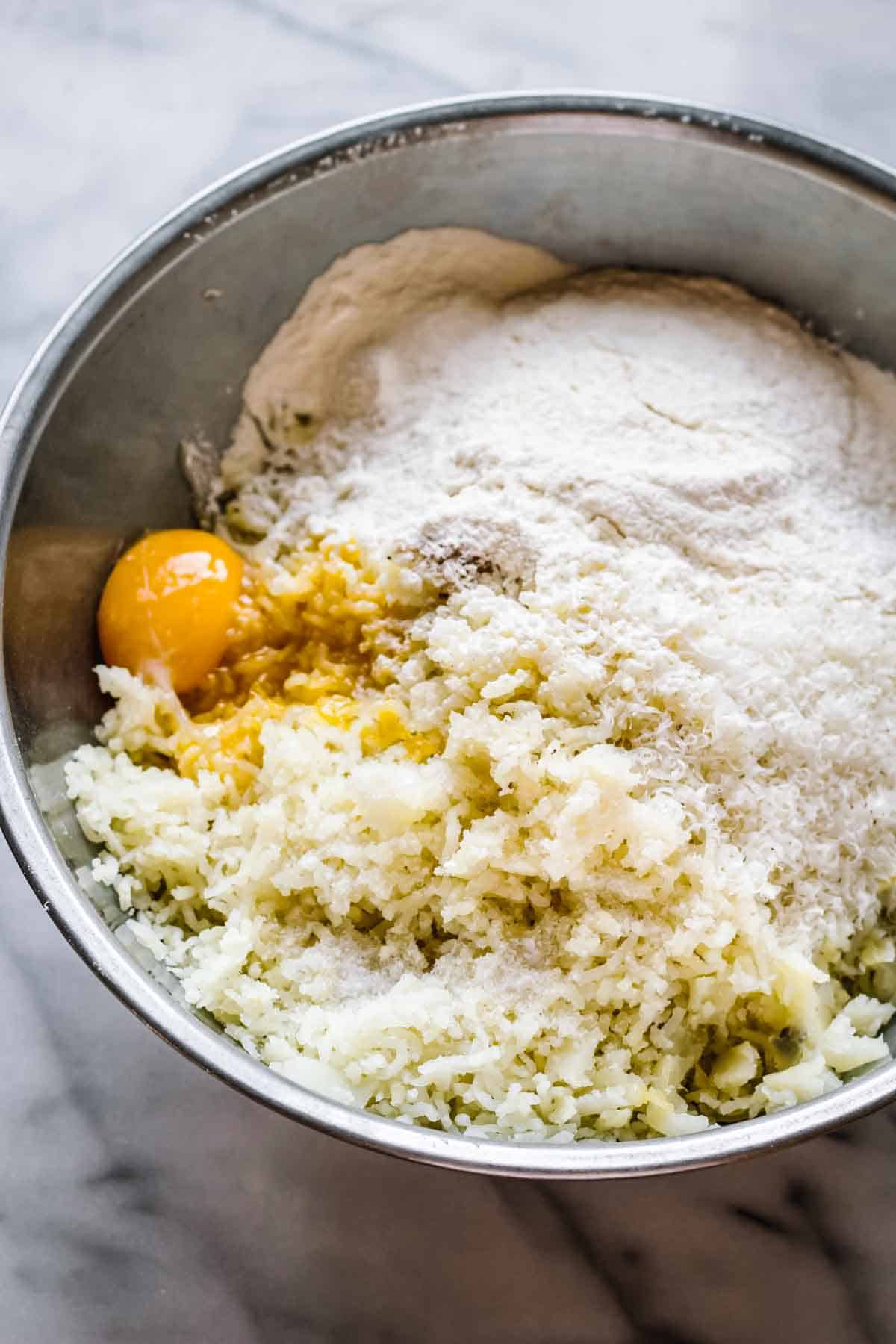 A bowl with riced potatoes, egg, and flour.