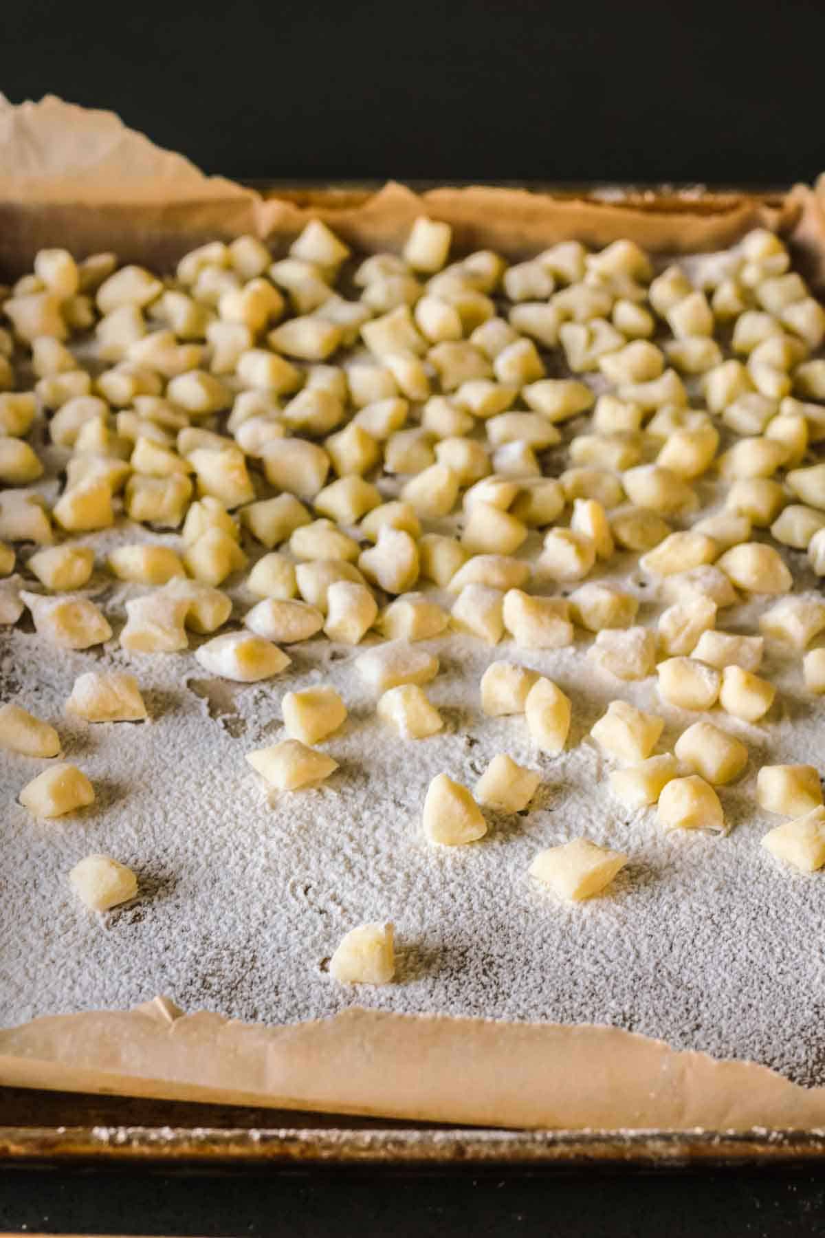 Freshly cut homemade potato gnocchi on a floured baking sheet.