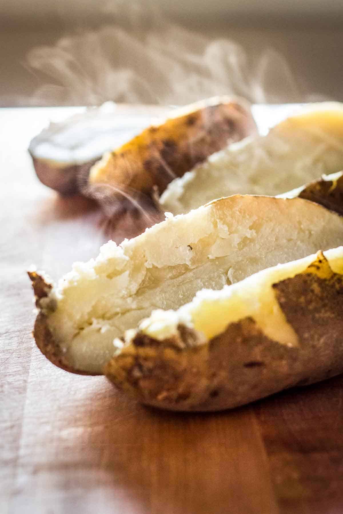 Baked potatoes cut open and steaming.