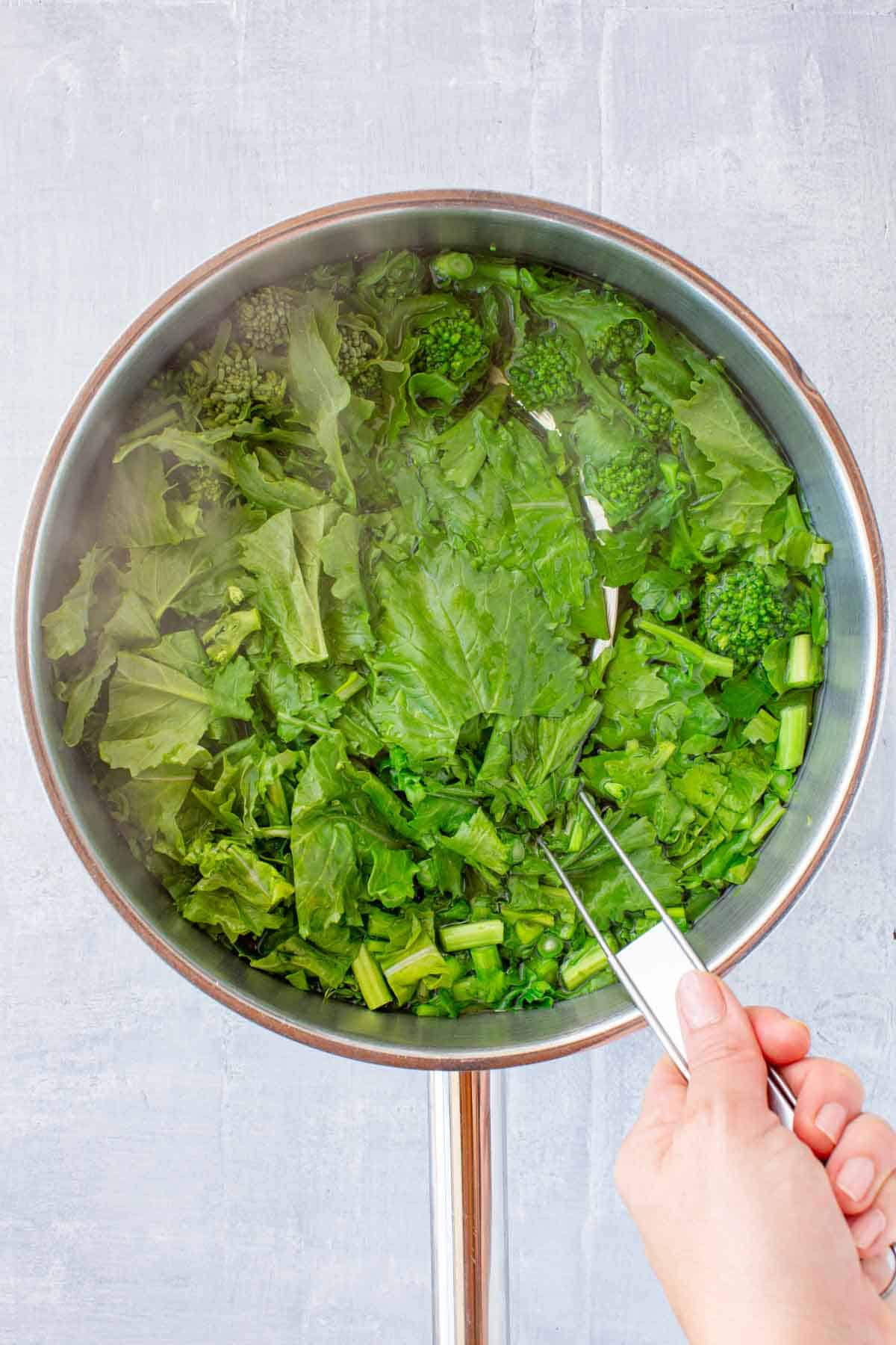 Scooping leafy greens out of a pot of boiling water.