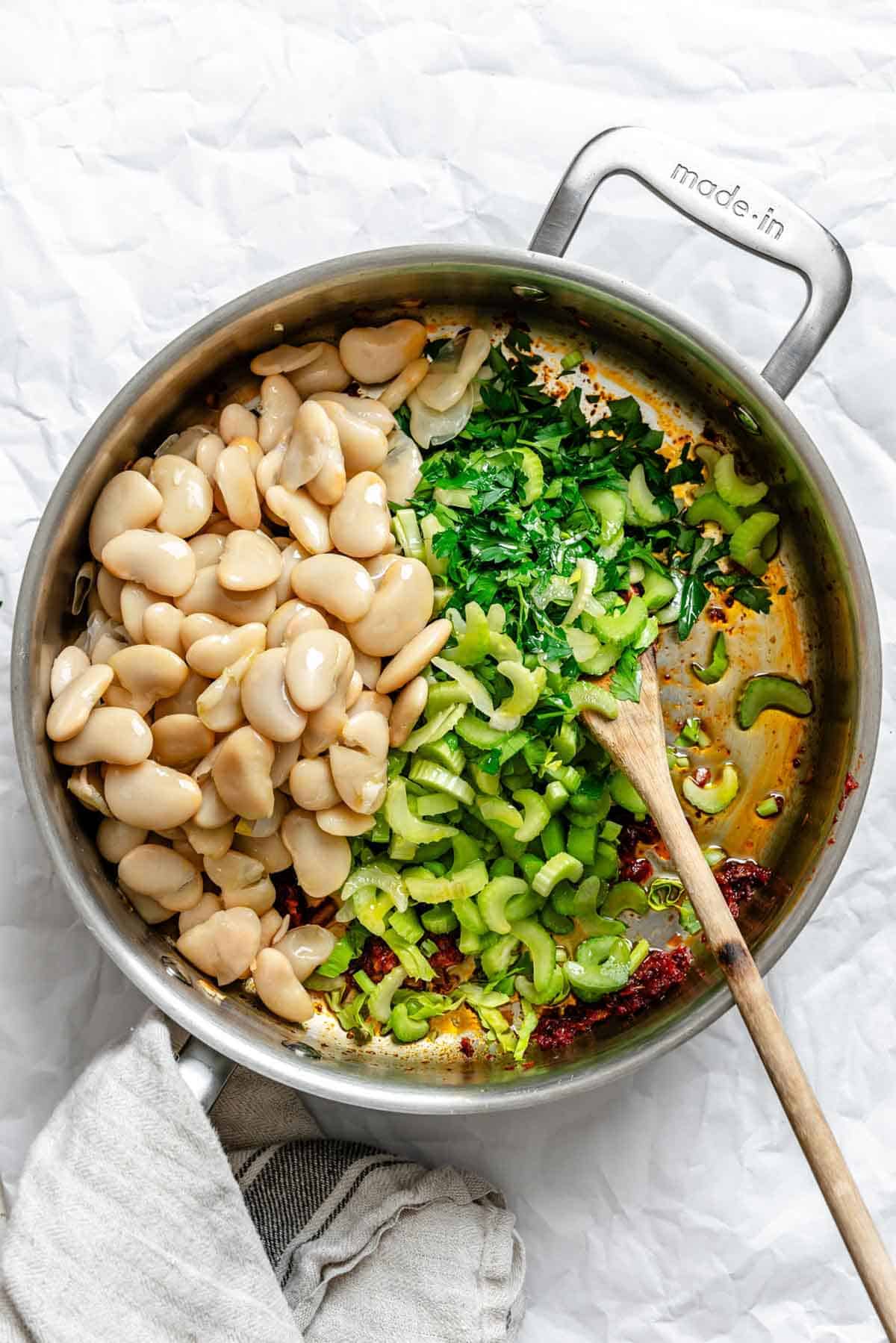 Adding beans, celery and parsley to a pan.