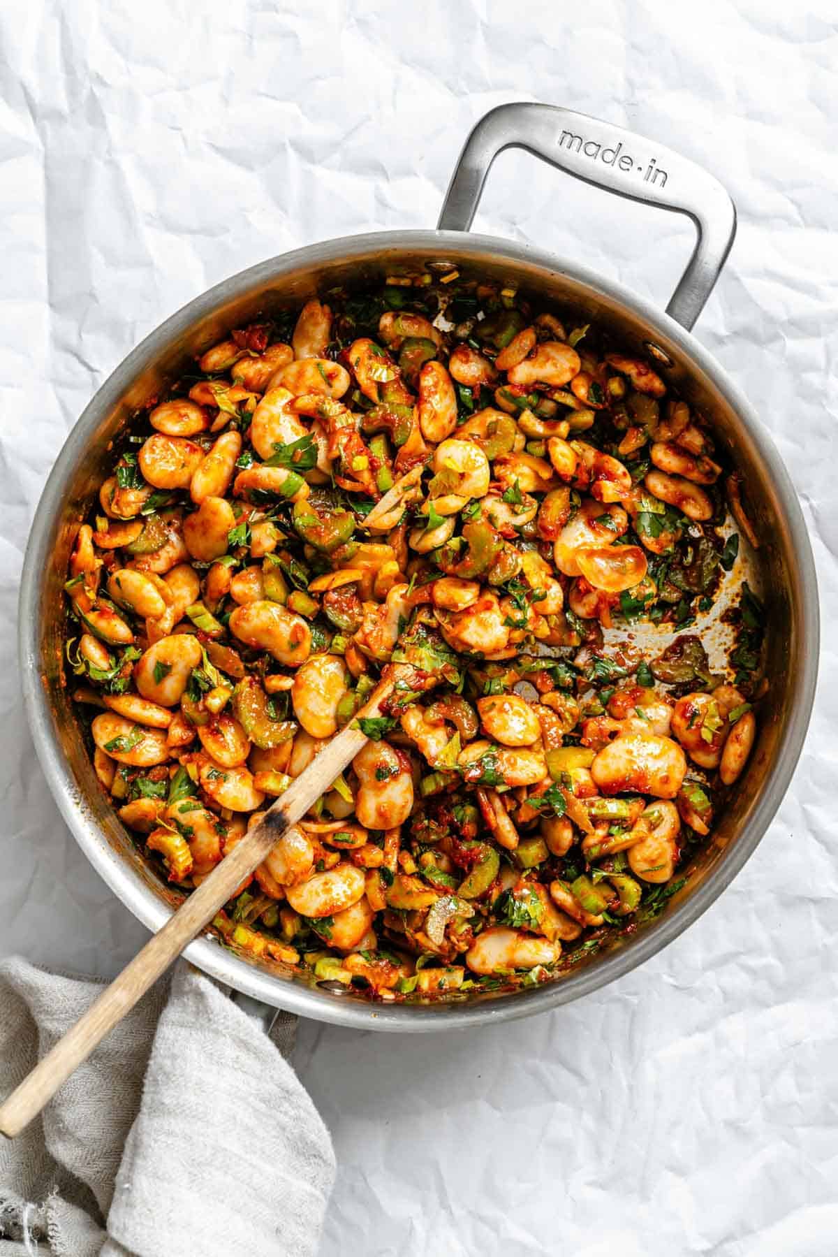 Warm gigante bean salad mixed together in a saute pan.