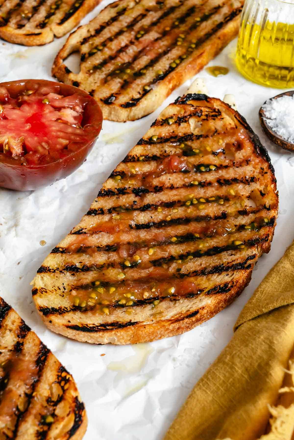 Close-up of pan con tomate, showing visible seeds and olive oil drizzled over the top.
