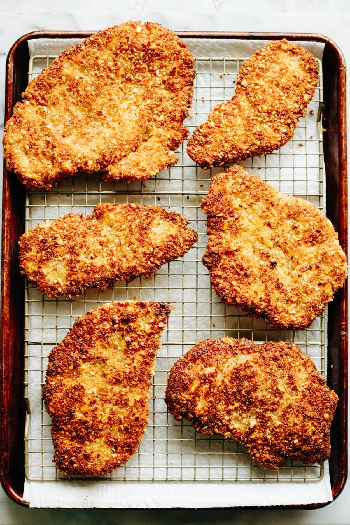 Close-up of crispy almond crusted chicken cutlets on a wire rack, highlighting the golden textured coating and crunchy exterior.