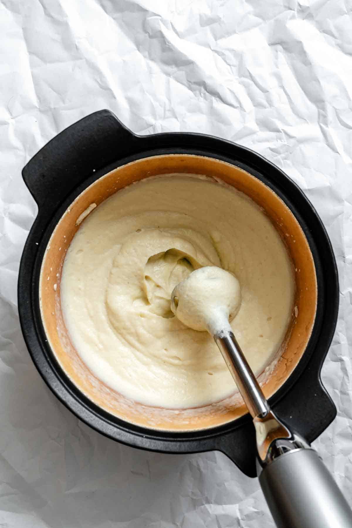 Smooth, creamy celery root and parsnip puree in a black Dutch oven with an immersion blender. The puree has a silky, pale beige texture after being blended.