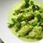 Macro view of tender spring pea gnocchi topped with fresh herbs and bright green peas in a silky sauce.