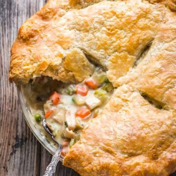Overhead shot of the chicken pot pie with a golden crust that has a slice missing.