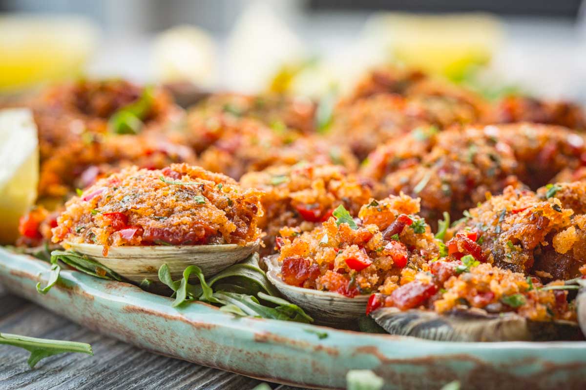 Golden, crispy stuffed clams with bacon and peppers served on a rustic ceramic platter.